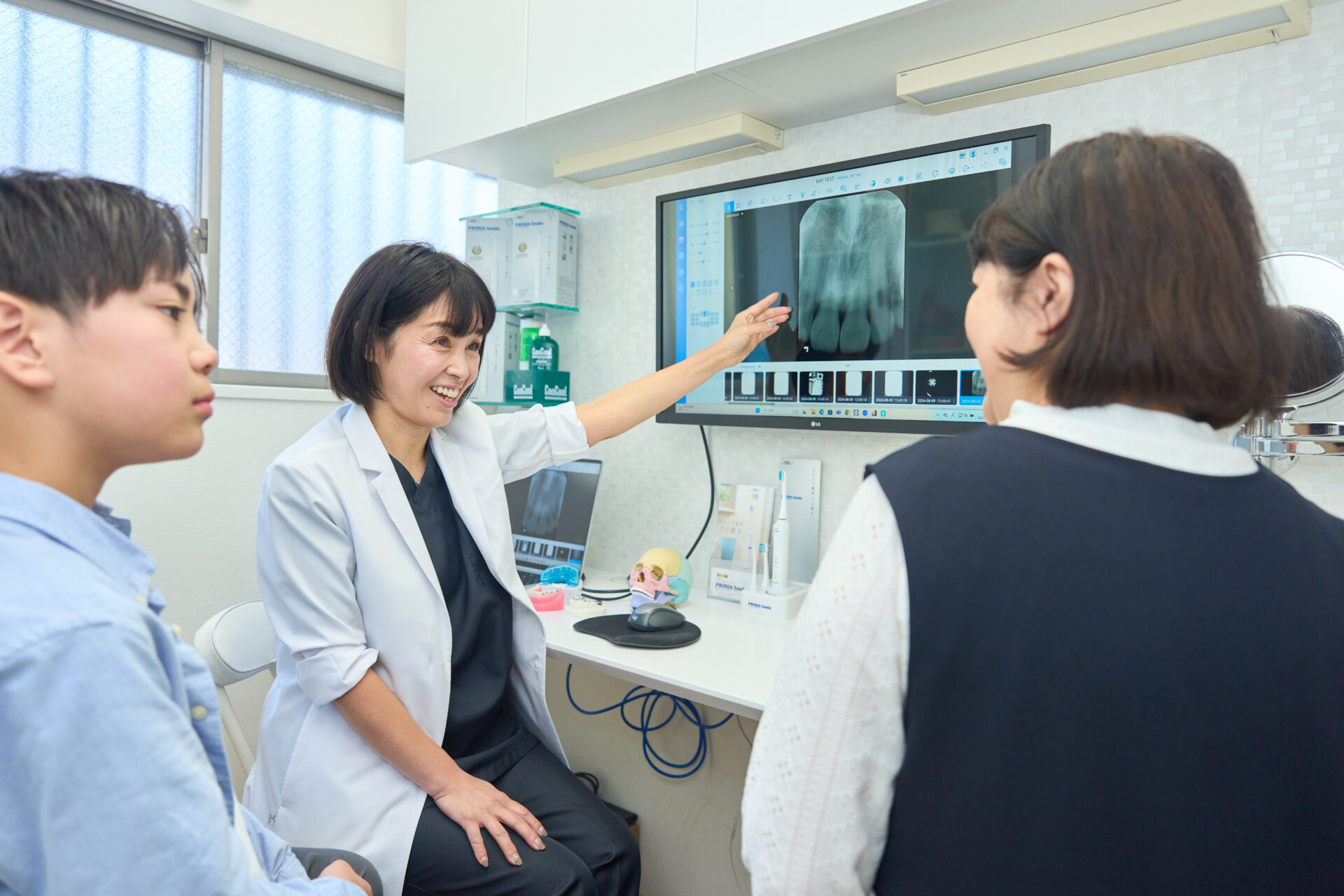 歯のレントゲン写真を使って患者に説明をする女性歯科医師