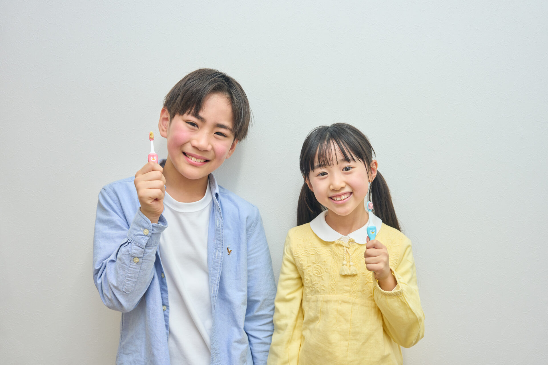 男の子と女の子が笑顔で歯ブラシを持っている